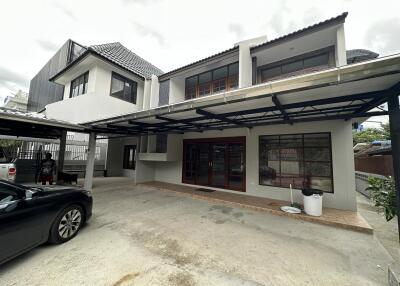 Exterior view of a two-story residential building with a covered carport and driveway