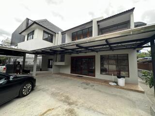 Exterior view of a two-story residential building with a covered carport and driveway