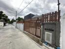 Street view of the property's entrance with a tall brown wooden gate