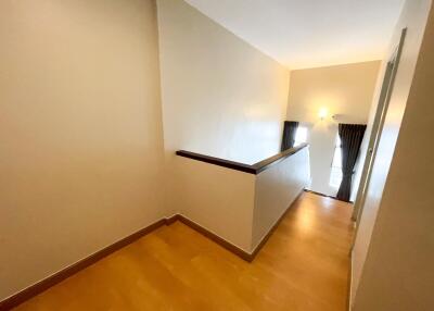 Well-lit hallway with wooden flooring and a balcony view.