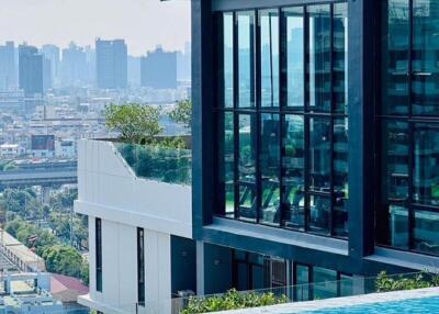 Modern building with glass windows and city view, featuring an infinity pool.