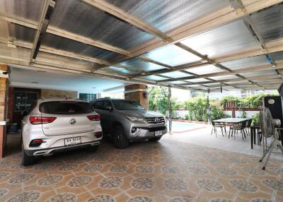 Two cars parked in a tiled garage with a partially transparent roof