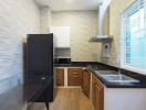 Modern kitchen with black fridge, wooden cabinets, and stainless steel sink