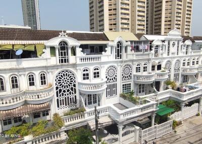 Exterior view of a white multi-story residential building with intricate window designs