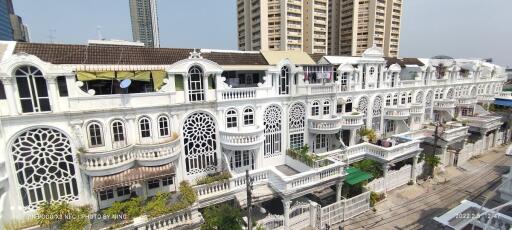 Exterior view of a white multi-story residential building with intricate window designs