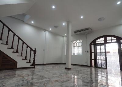 Spacious living area with staircase, marble flooring, and large windows