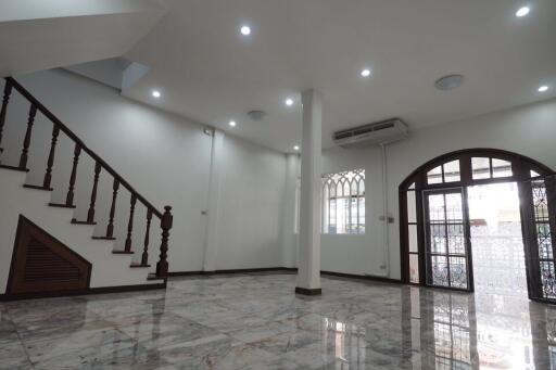 Spacious living area with staircase, marble flooring, and large windows