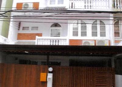 Front view of a multi-level building with balconies and a gated entrance