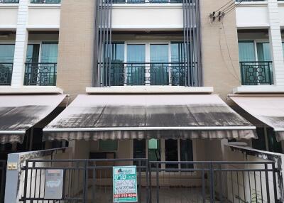 Front view of a multi-story residential building with balconies and awnings