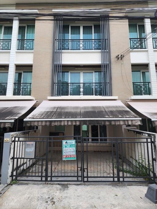 Front view of a multi-story residential building with balconies and awnings