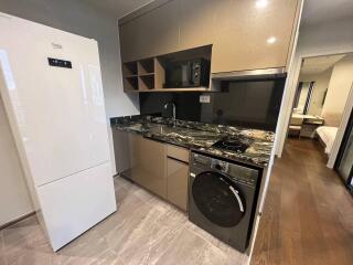 Modern kitchen with appliances including refrigerator, microwave, and washing machine