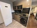 Modern kitchen with appliances including refrigerator, microwave, and washing machine