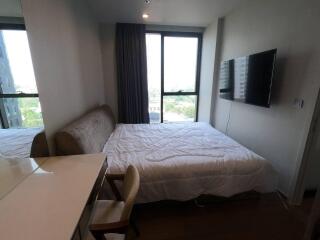 Bedroom with a large window, bed, mounted TV, desk, and chair