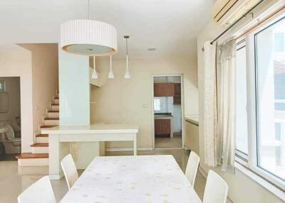 Modern dining area with a table and chairs, adjacent to stairs and a kitchen