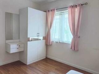 Bright minimalist bedroom with a closet, vanity, and window with pink curtains