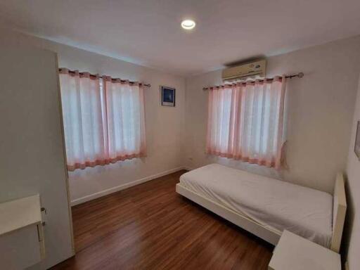 Spacious bedroom with wooden flooring, large windows, and an AC unit