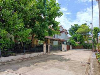 A view of the residential property from the street showing multiple houses surrounded by trees.