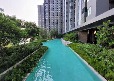 Outdoor swimming pool with lush greenery and modern apartment buildings