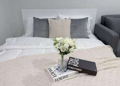 Cozy bedroom with a double bed, pillows, and a vase with flowers