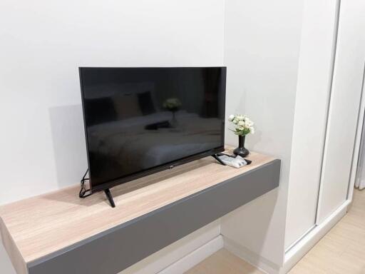 Modern bedroom with TV and small flowers on floating shelf