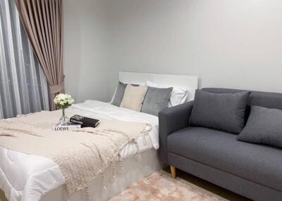 Cozy bedroom with a bed, grey sofa, and decor