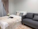 Cozy bedroom with a bed, grey sofa, and decor