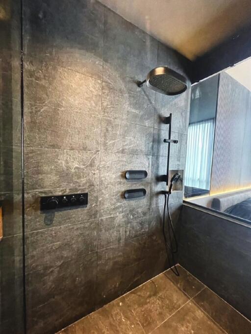 Modern bathroom with a large rain shower head and dark tiles