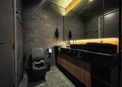 Modern bathroom with dark tiles and wooden details