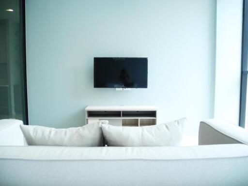 Modern living room with wall-mounted TV and white sofas