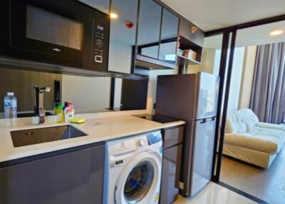 Modern kitchen area with appliances and a view into the living room