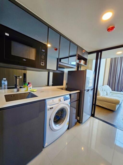 Modern kitchen area with appliances and a view into the living room