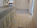 Simple kitchen with tiled walls and floor, featuring a sink and shelves