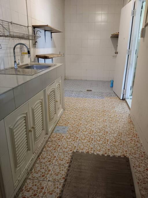 Simple kitchen with tiled walls and floor, featuring a sink and shelves