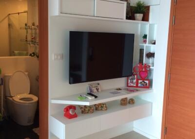 Living room with wall-mounted TV and adjacent bathroom