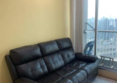 Living room with a black leather sofa and a view of the city through a window