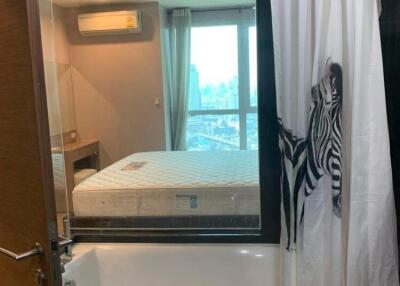 Bathroom with a bathtub and a large mirror reflecting a bedroom