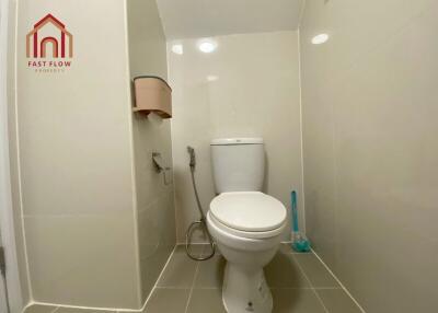 Bathroom with toilet, bidet spray, and toilet brush