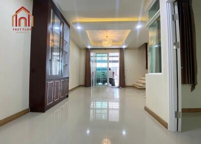 Spacious and modern living room with large windows, chandelier, and glass cabinet