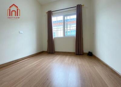 Empty bedroom with wooden flooring, window with curtains and natural light