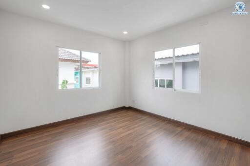 Empty bedroom with wooden flooring and large windows