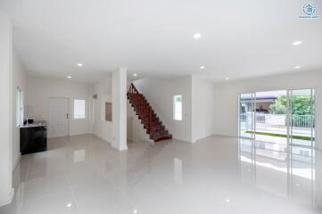 Spacious and well-lit living room with large windows, staircase, and glossy tiled floors