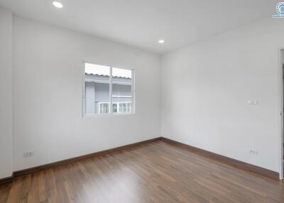 Empty bedroom with wooden floor and windows