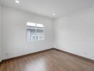 Empty bedroom with wooden floor and windows