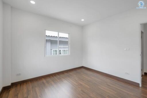 Empty bedroom with wooden floor and windows