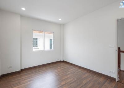 Empty bedroom with a window and wooden floor