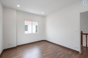 Empty bedroom with a window and wooden floor