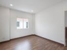 Empty bedroom with a window and wooden floor