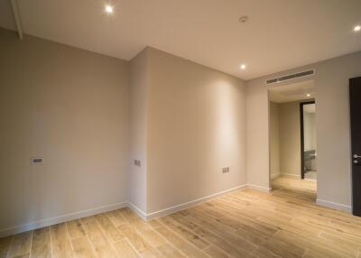 Empty bedroom with wooden flooring and recessed lighting