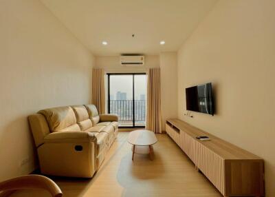 Modern living room with sofa, wall-mounted TV, and large window