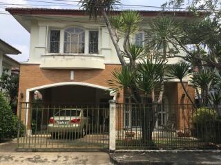 Two-story house with a car parked in the driveway and a small garden